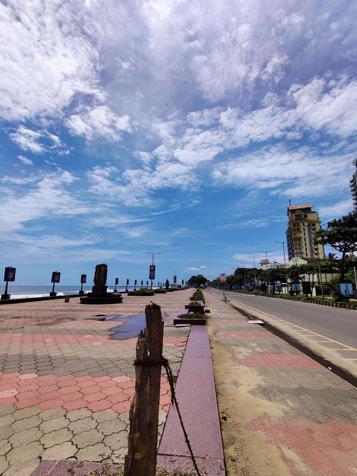 Kozhikode Beach Road: the tiled promenade and sculpture court beside the Arabian Sea, with the four-lane beach road and hotel frontage alongside