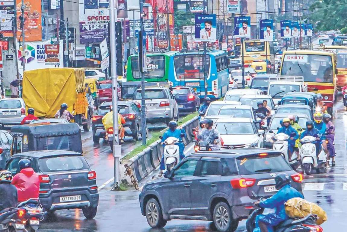 Evening traffic on Mavoor Road, Kozhikode: buses, cars and two-wheelers queued nose to tail across both carriageways in the rain
