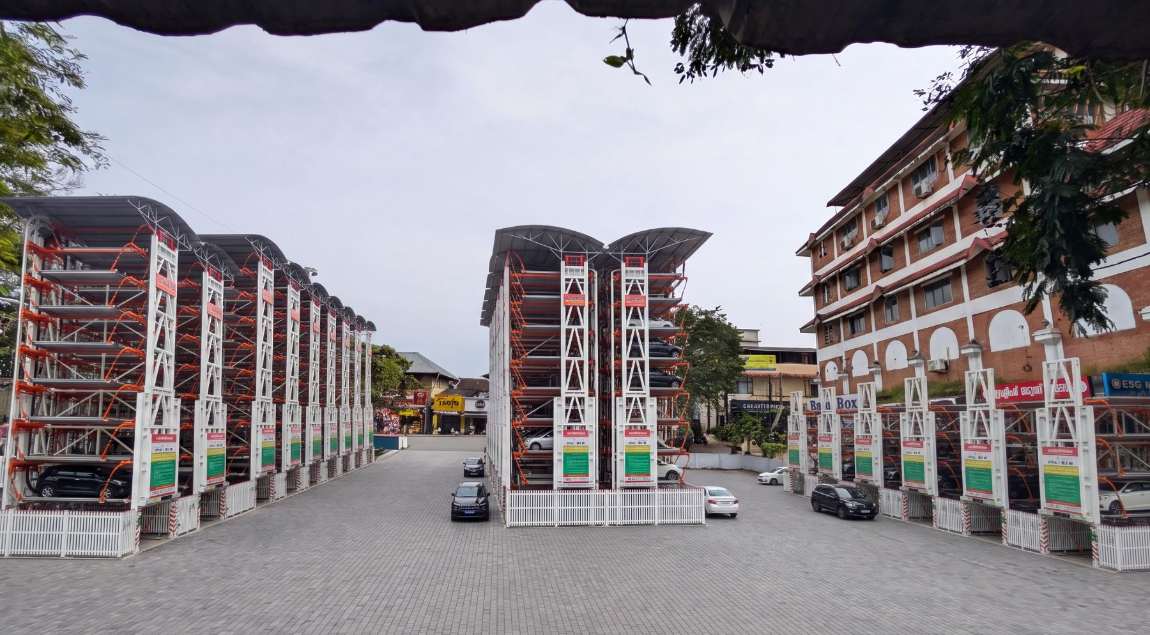 The SM Street yard rebuilt with rows of white and orange multi-level rotary parking towers along both flanks and a pair at the head, a paved forecourt between them and the market buildings beyond